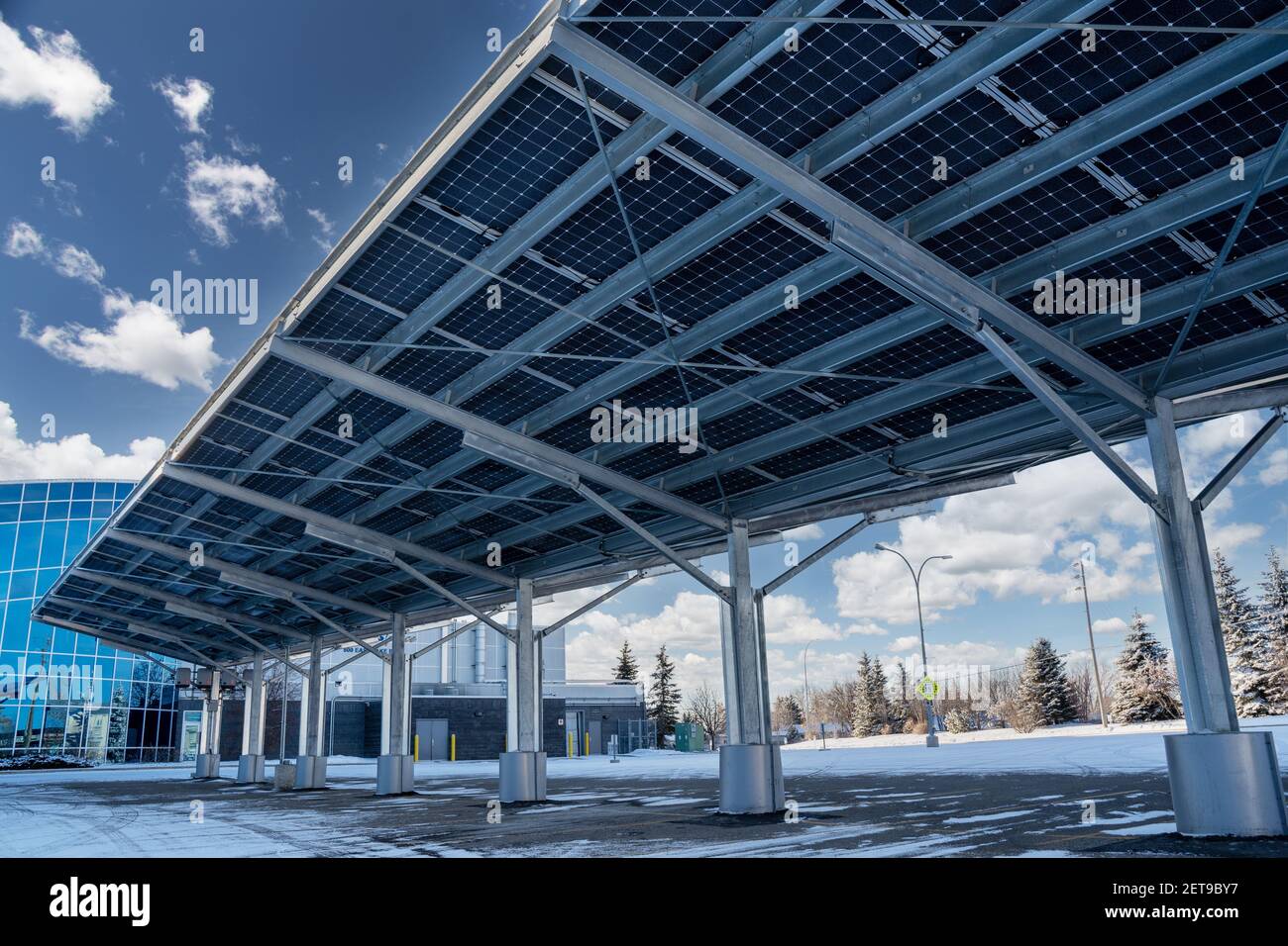 A modern solar carport for public vehicle parking is outfitted with solar panels producing renewable energy Stock Photo