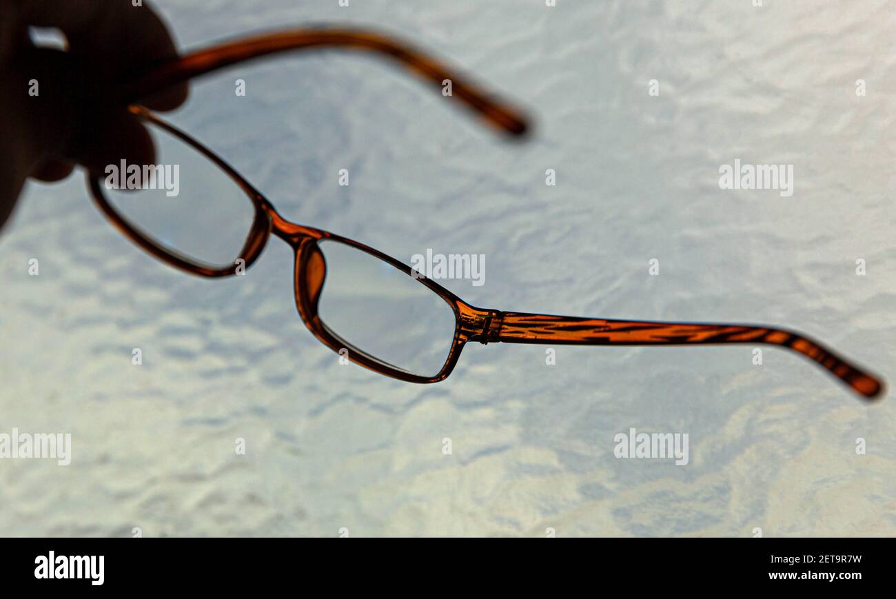 A pair of glasses held up by two fingers. Stock Photo