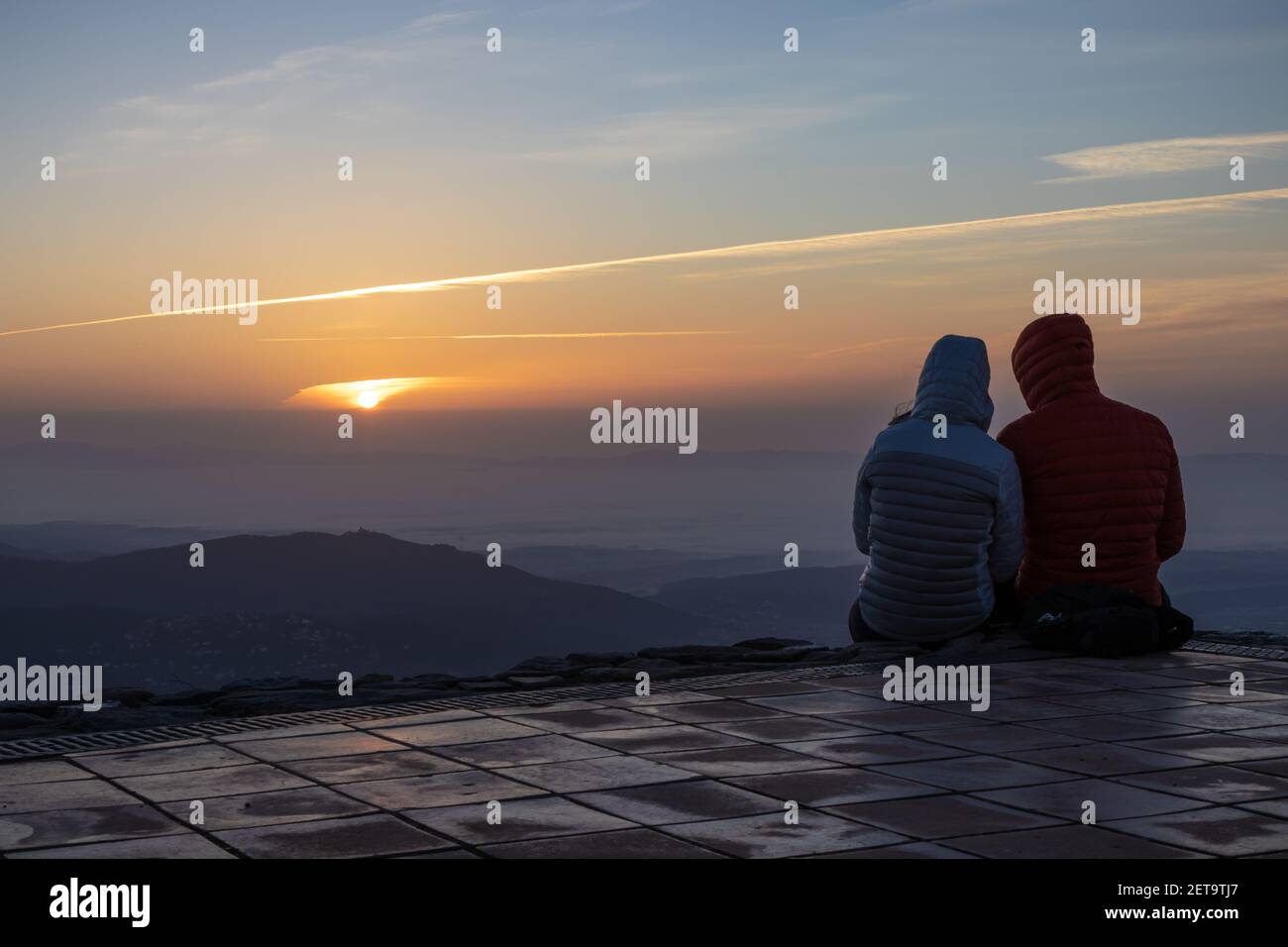Couple watching the amazing sunrise from the top of La Mola Mountain in the Parc natural de Sant Llorenc del Munt i l'Obac, Valles Occidental, Catalon Stock Photo