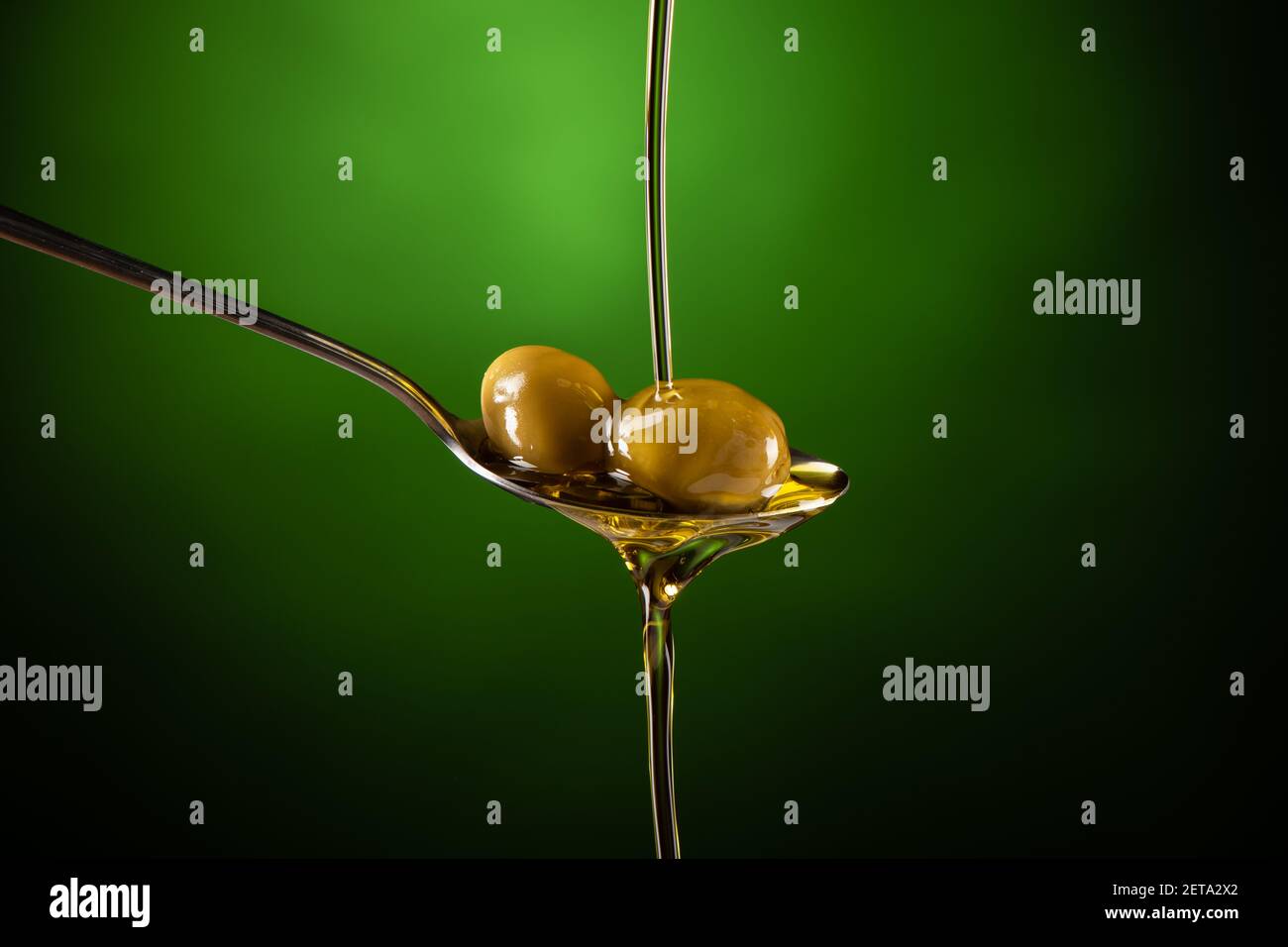 Olive oil poured into a spoon on a green background Stock Photo - Alamy