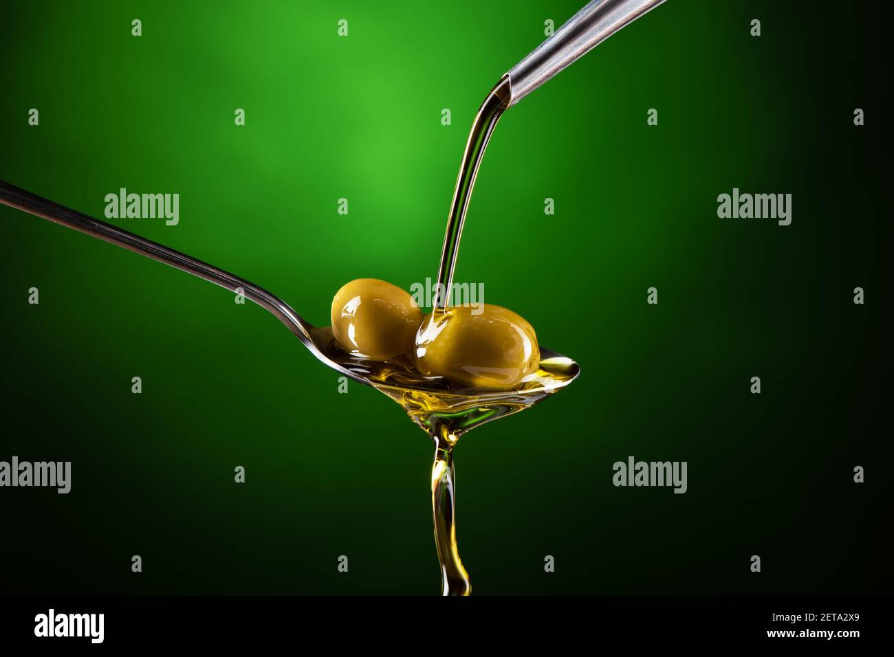 Olive oil poured into a spoon on a green background Stock Photo - Alamy