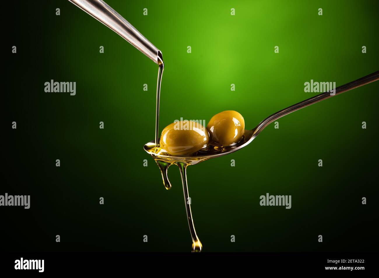 Olive oil poured into a spoon on a green background Stock Photo - Alamy