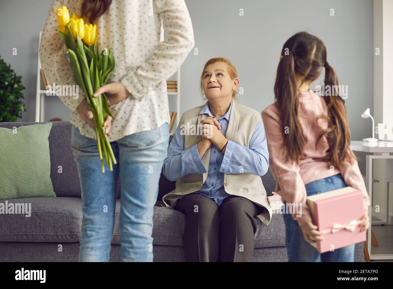 Joyful senior woman receives congratulations on Women's Day from her daughter and granddaughter. Stock Photo