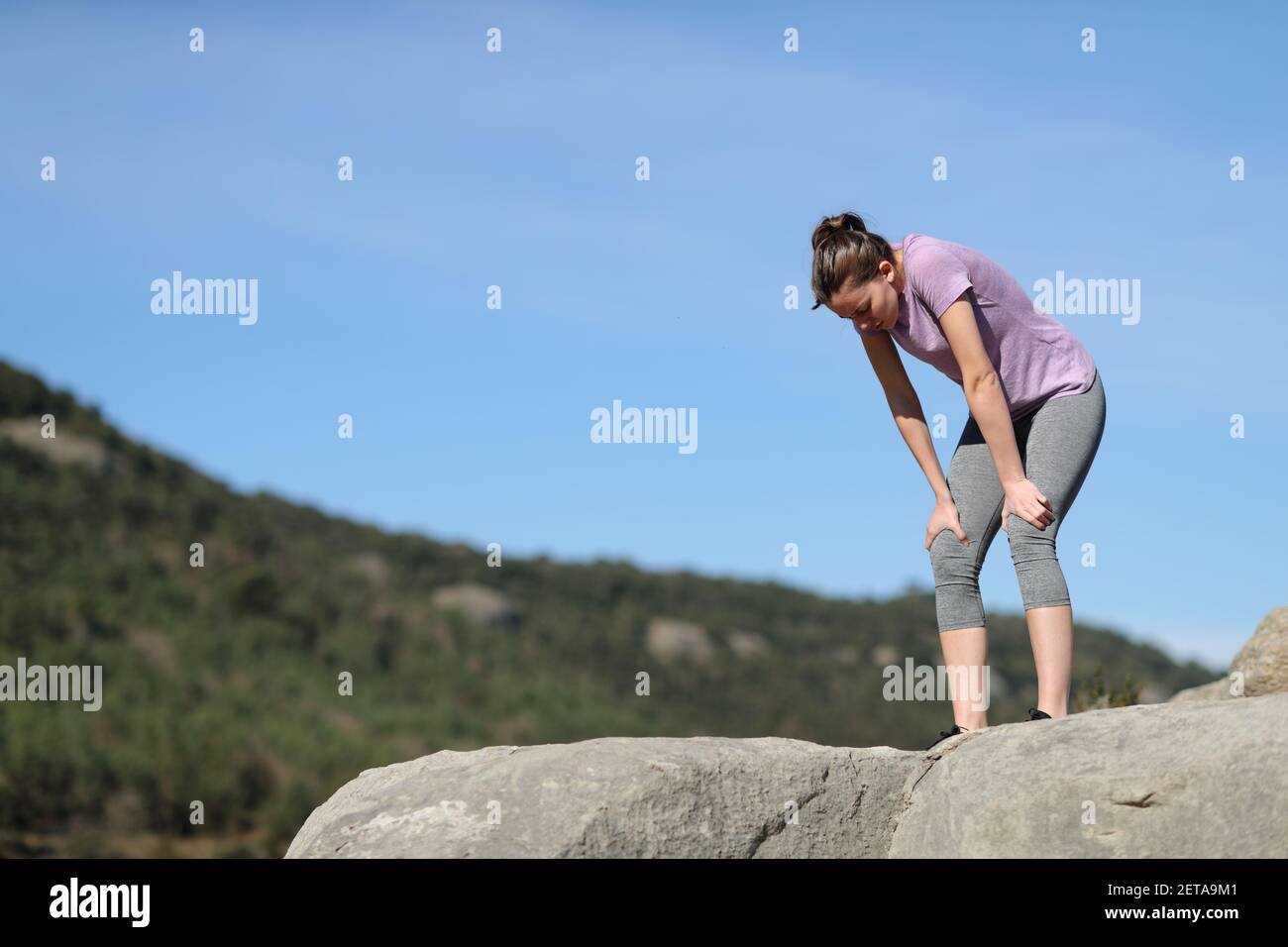 Exhausted jogger resting after running in the mountain Stock Photo