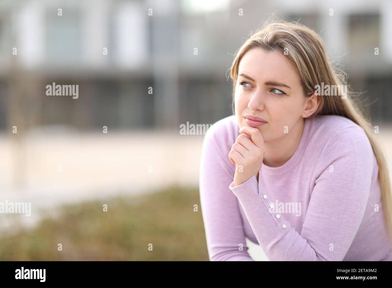 Pensive serious teen looking sideways sitting in the street Stock Photo