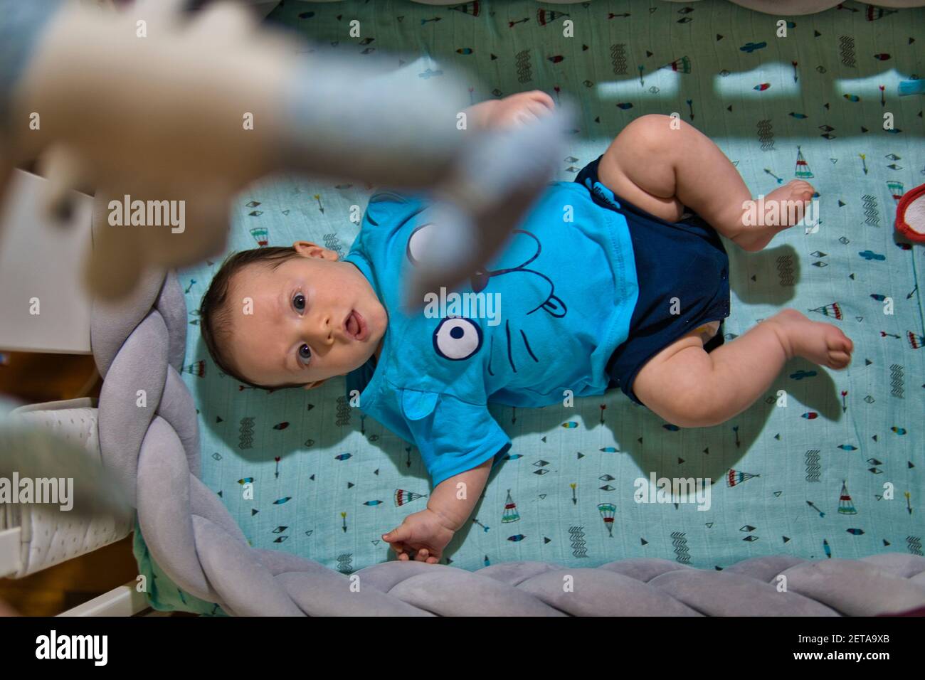 two month old baby lying in a crib on his back awake Stock Photo Alamy