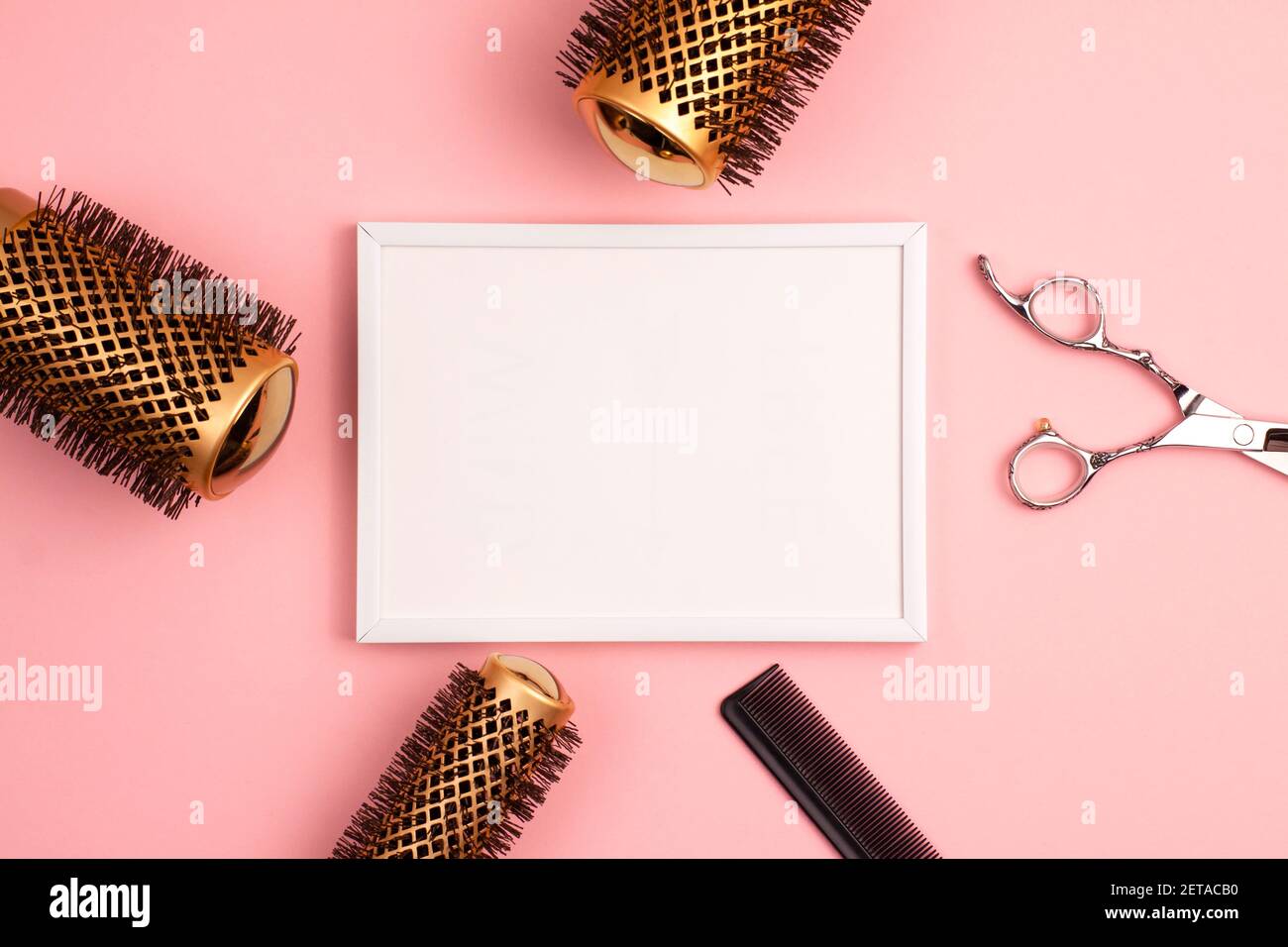 Plastic picture frame mockup flat lay of professional hair cutting shears, gold round hair brush for styling, comb for separating hair template and pi Stock Photo