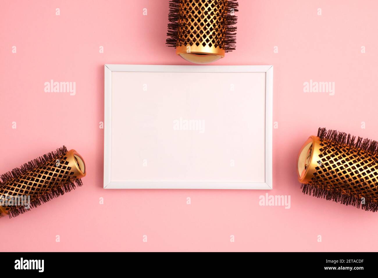 Plastic frame flat lay of set of professional gold round hair brushes for styling at the right of the image template with copy space on pink. Hairdres Stock Photo