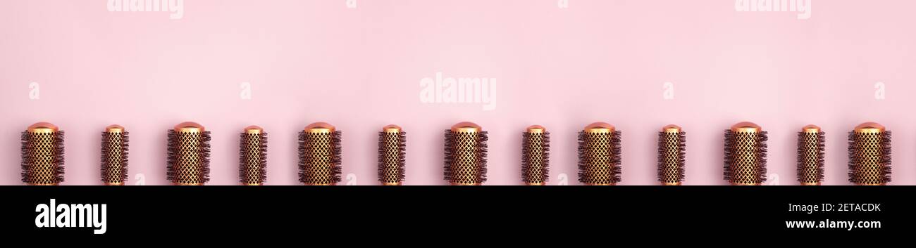 Banner flat lay of set of professional gold round hair brushes for styling at the bottom of the image template with copy space on pink background. Hai Stock Photo