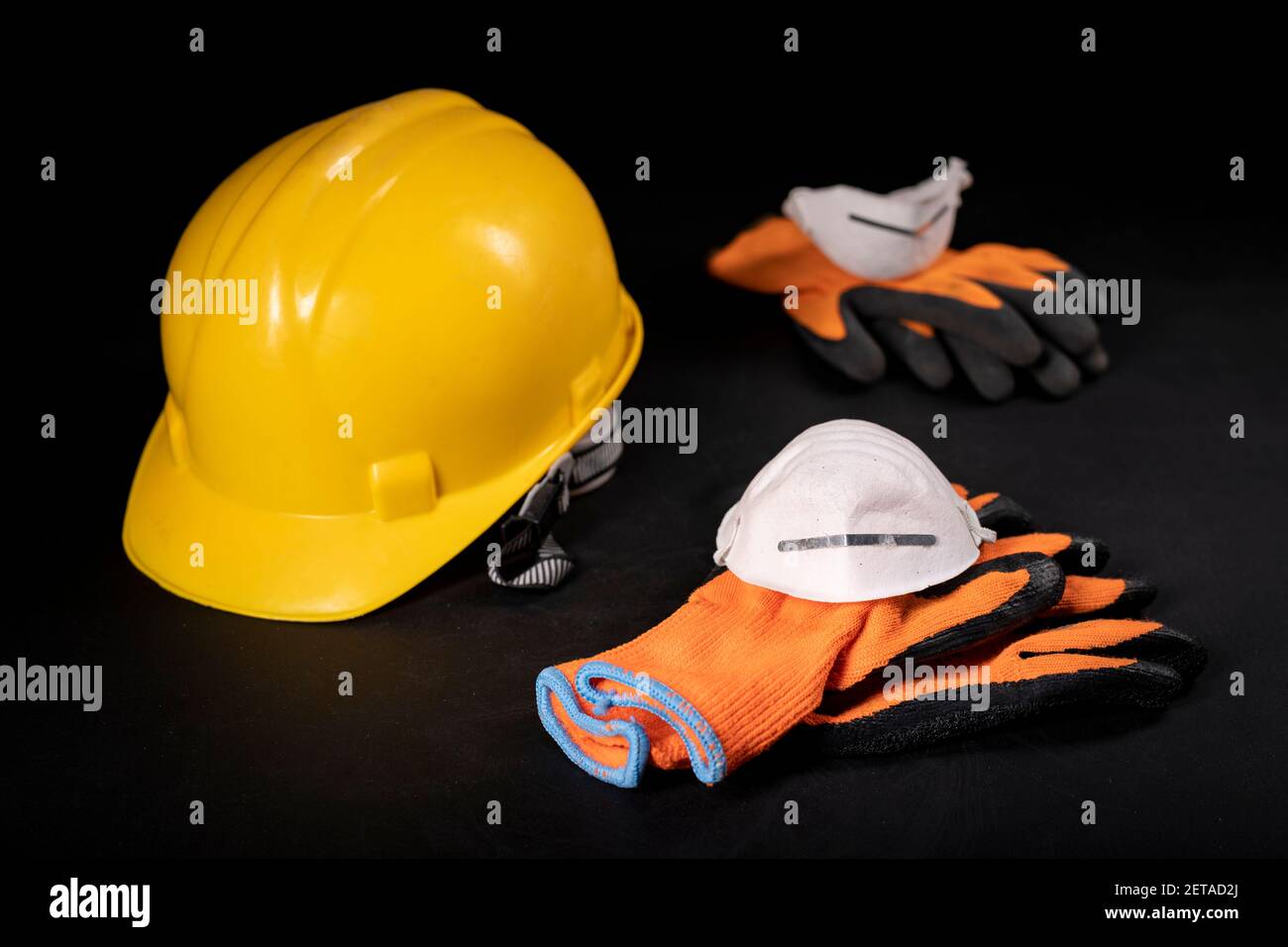 Work gloves, hard hat and dust mask. Protective accessories for construction workers. Dark background. Stock Photo