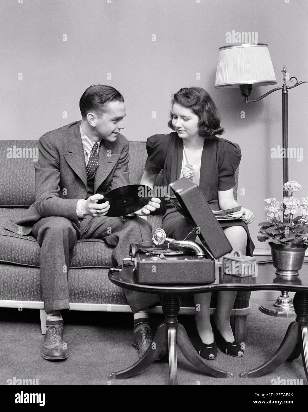 1930s 1940s YOUNG DATING COUPLE MAN AND WOMAN SITTING ON COUCH TOGETHER LISTING TO MUSIC ON PORTABLE RECORD PLAYER - s8949 HAR001 HARS NOSTALGIC PAIR ROMANCE BEAUTY SUBURBAN URBAN OLD TIME NOSTALGIA MEDIA OLD FASHION 1 SILLY JUVENILE COUCH COMMUNICATION YOUNG ADULT BALANCE COMIC TEAMWORK STRONG PLEASED JOY LIFESTYLE FEMALES HOME LIFE LUXURY COPY SPACE FRIENDSHIP FULL-LENGTH LADIES PERSONS CARING MALES TEENAGE GIRL TEENAGE BOY ENTERTAINMENT PORTABLE B&W DATING TEMPTATION HUMOROUS HAPPINESS CHEERFUL LEISURE AND CHOICE EXCITEMENT RECREATION COMICAL INNOVATION ON TO SMILES CONNECTION 78 RPM Stock Photo