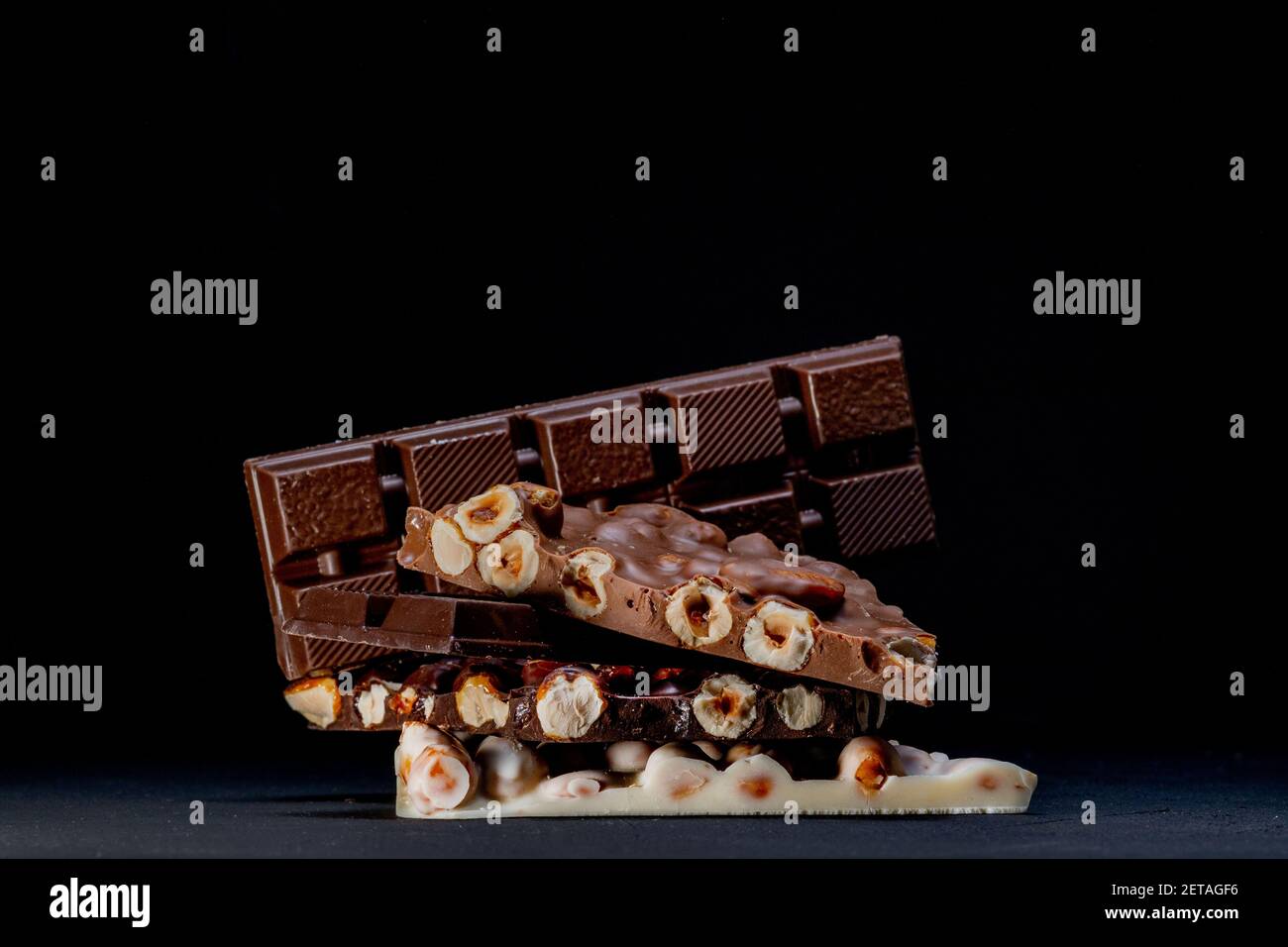 Dark and white chocolate with hazelnuts on a black background Stock Photo