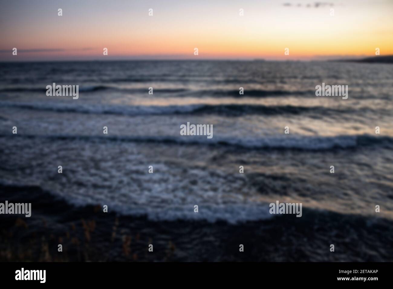 Defocused colorful summer landscape, sunset and sea waves in the resort town of Gelendzhik. Cloudless sky and cargo ships on the horizon. Russia Stock Photo