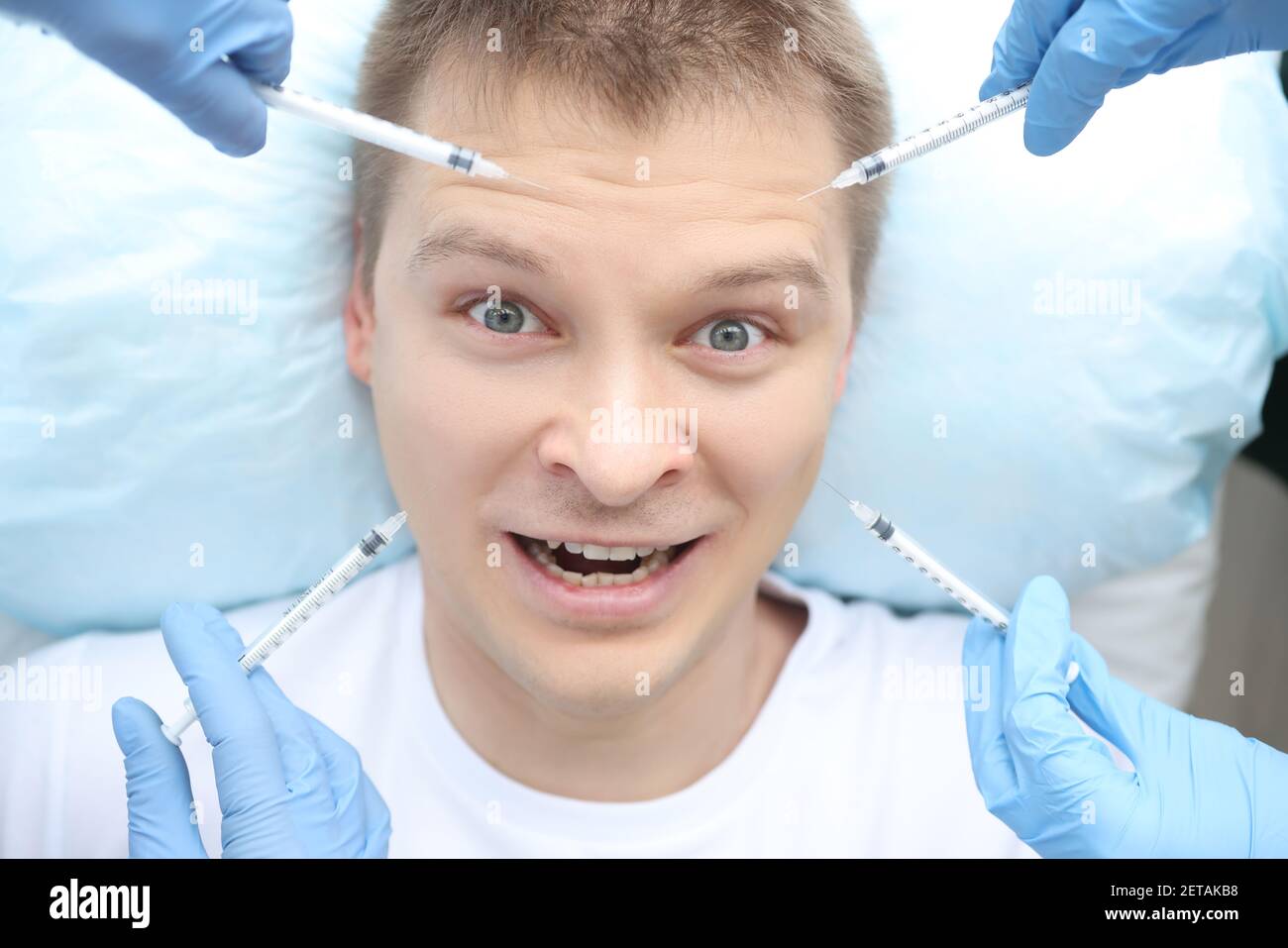 Portrait of frightened man who is being given several injections at ...