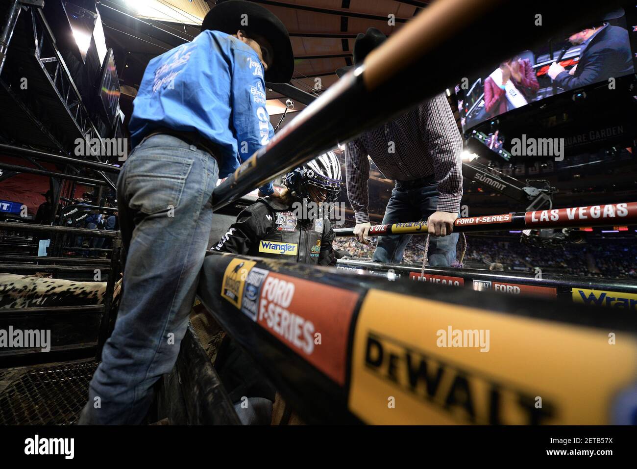 A rider helps another bull rider get ready he sits on a bull in a chute ...