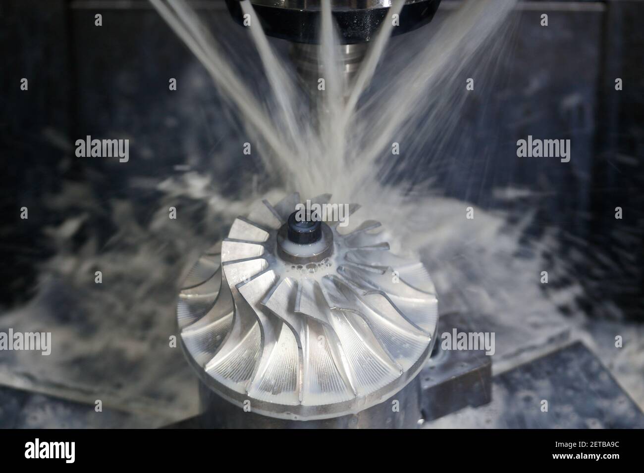 Turbine wheel milling process with coolant on five axis CNC machining center. Stock Photo