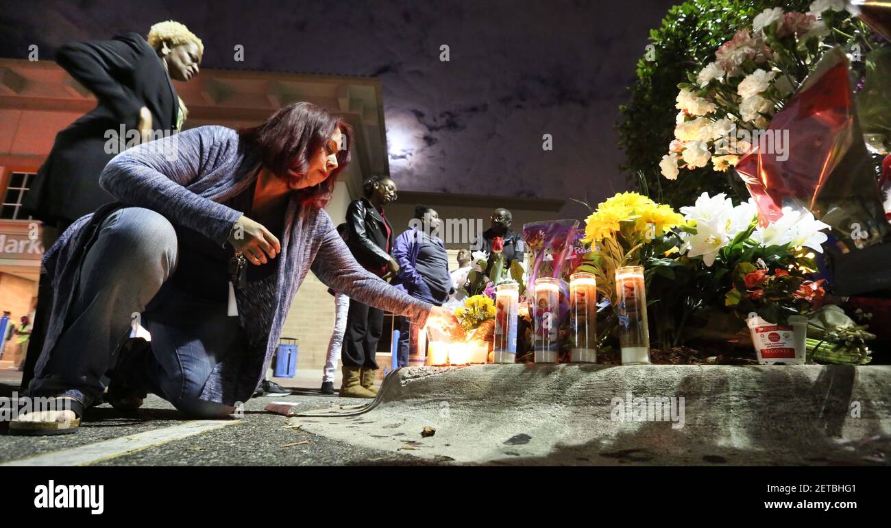 Tricia Dennis and Orlando city commissioner Regina Hill, far left, pay their respects at a pop-up memorial in front of the Pine Hills Wal-mart, before a candlelight vigil to honor the the Orlando, Fla., police officer killed by an assailant at the Wal-mart, and an Orange deputy who was killed while responding to the OPD fatality, Tuesday, Jan. 10, 2017. (Photo by Joe Burbank/Orlando Sentinel/TNS) *** Please Use Credit from Credit Field *** Stock Photo