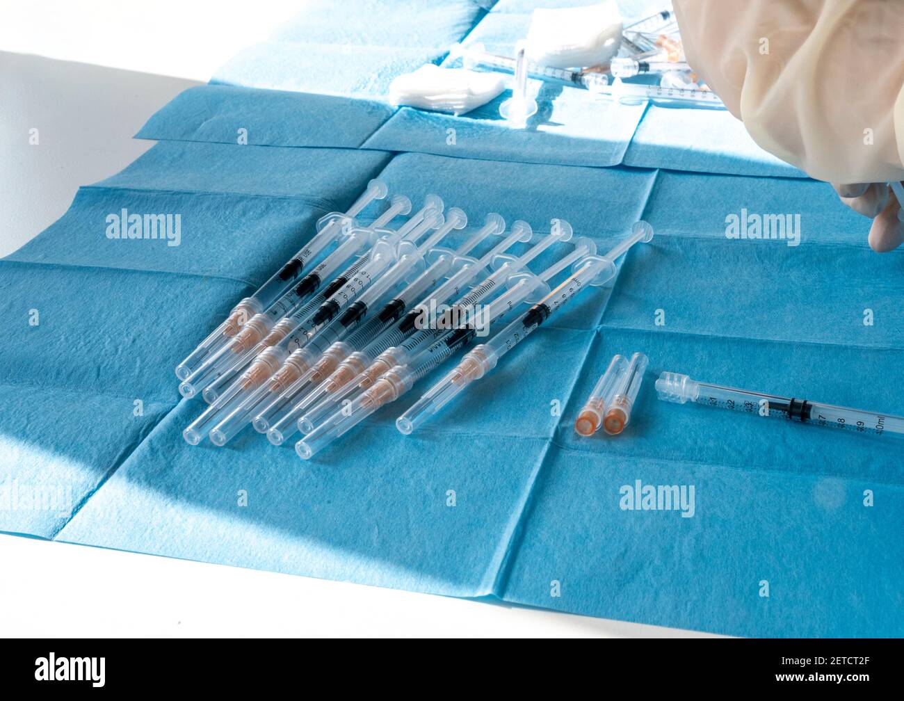 Medical worker prepare an injection of vaccine during a massive vaccination day at a healthcare centre.  Syringes in preparation and ready to use. Stock Photo