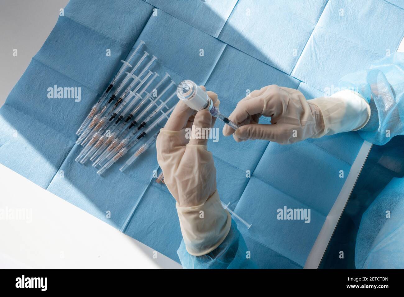 Medical worker prepare an injection of vaccine during a massive vaccination day at a healthcare centre.  Syringes in preparation and ready to use. Stock Photo