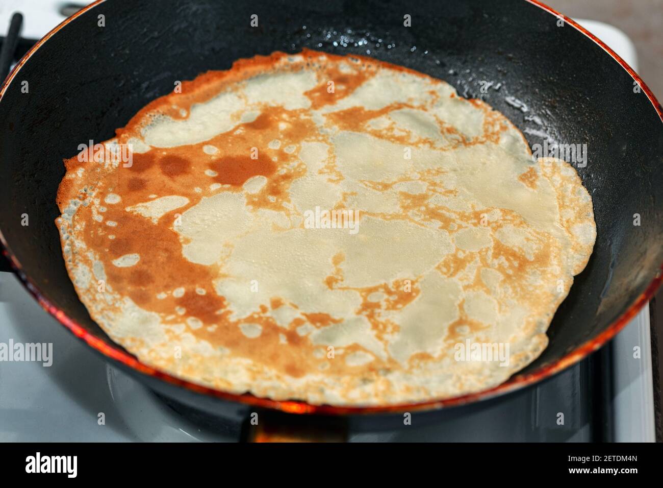 Pancake in a frying pan . Cooking delicious and highcalorie food Stock