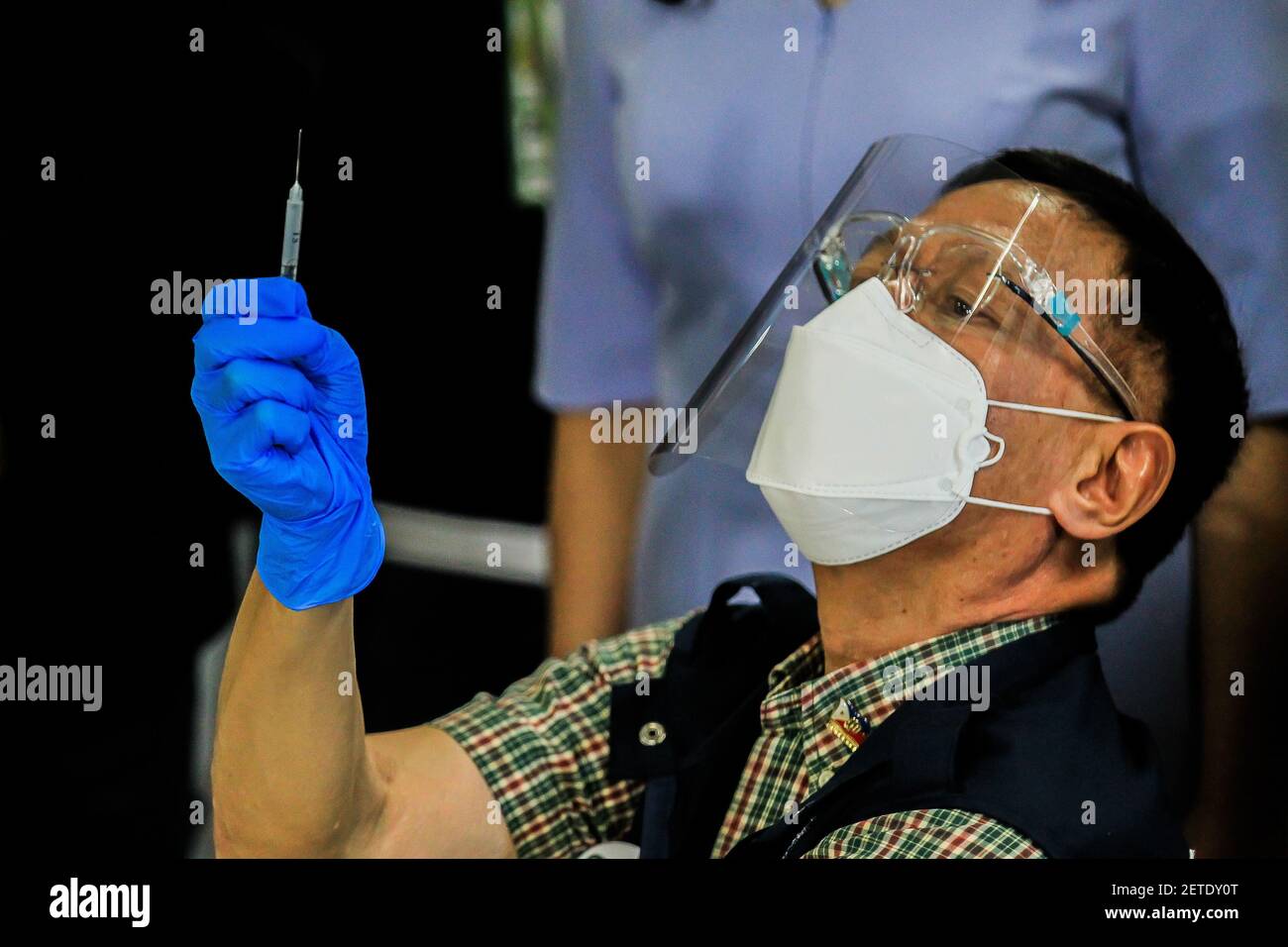 Beijing, China. 1st Mar, 2021. Philippine Department of Health Secretary Francisco Duque III looks at a syringe containing a shot of COVID-19 vaccine from China's Sinovac on the first day of the vaccination at the Lung Center of the Philippines in Manila, the Philippines on March 1, 2021. The Philippines launched its coronavirus vaccination campaign on Monday, less than a day after the arrival of the Sinovac vaccine CoronaVac donated by China. Credit: Rouelle Umali/Xinhua/Alamy Live News Stock Photo