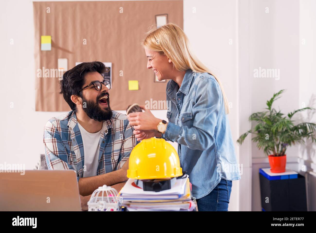 Two young and cheerful engineers are having a laugh during their break ...