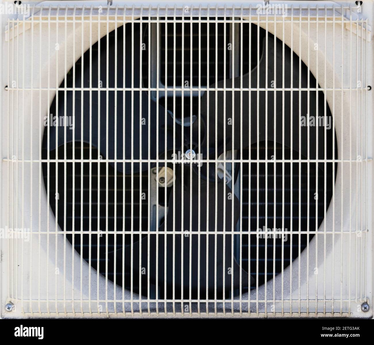 A metal fan is barely visible through the mazes of a condenser unit of an air conditioner set. Stock Photo