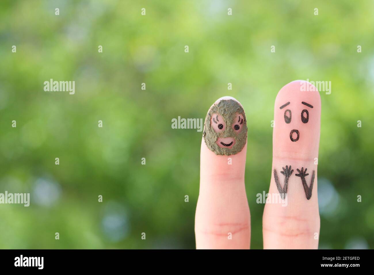 Fingers art of couple. Husband saw his wife with clay face mask and was afraid. Stock Photo