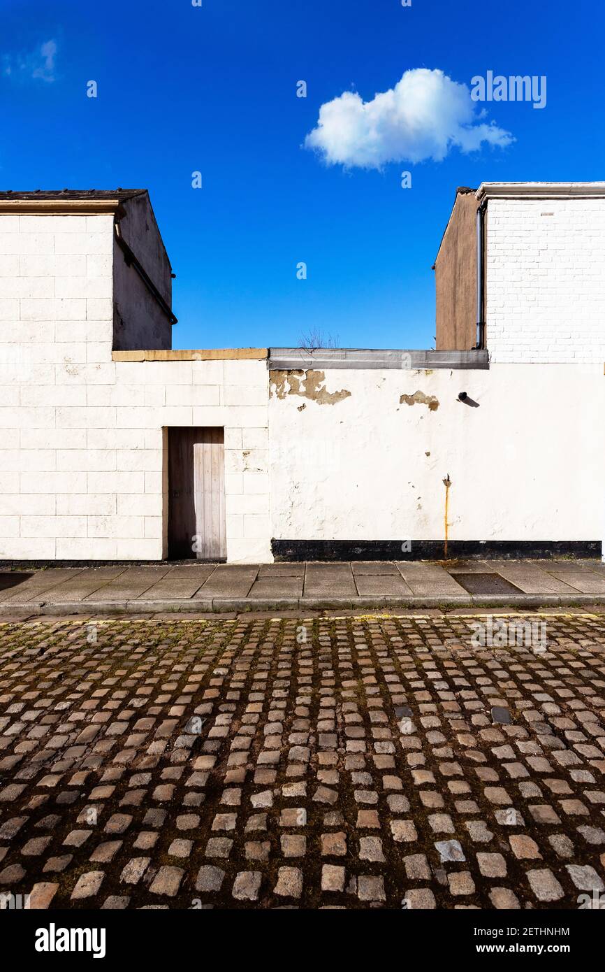 Graphic image of a cobbled Preston back street showing 2 properties, a back door and a lone cloud. Stock Photo