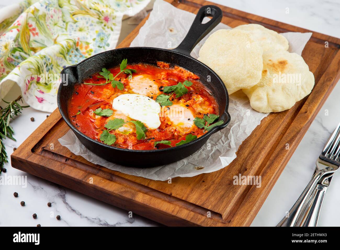 shakshuka - scrambled eggs with herbs, beans and tomatoes in a skillet with lean crispbread Stock Photo