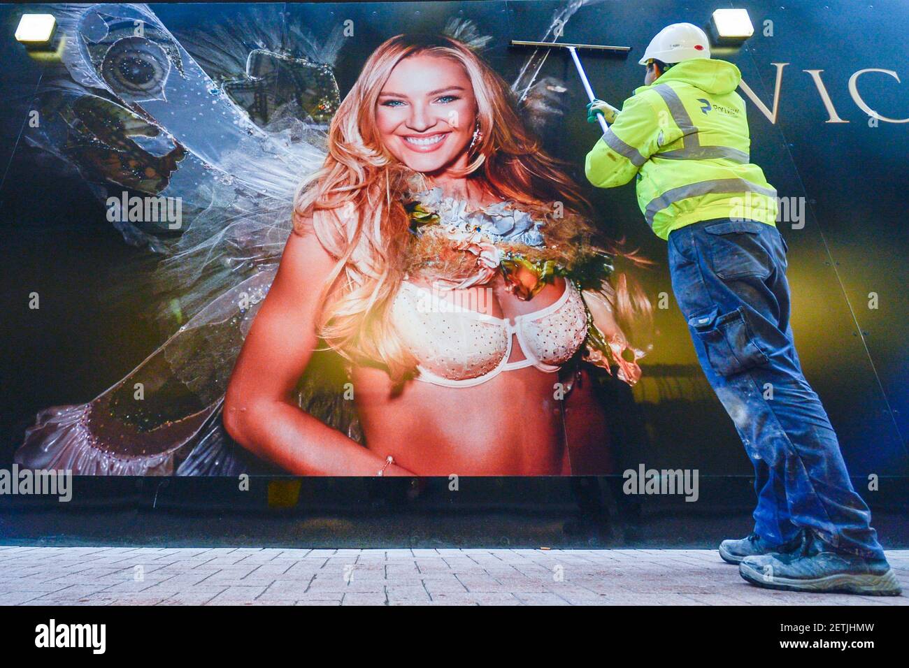A man cleans Victoria Secret billboard announcing the opening of