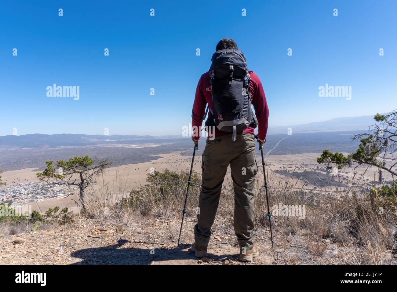 A back view of a male hiker standing on top of a hill enjoying ...