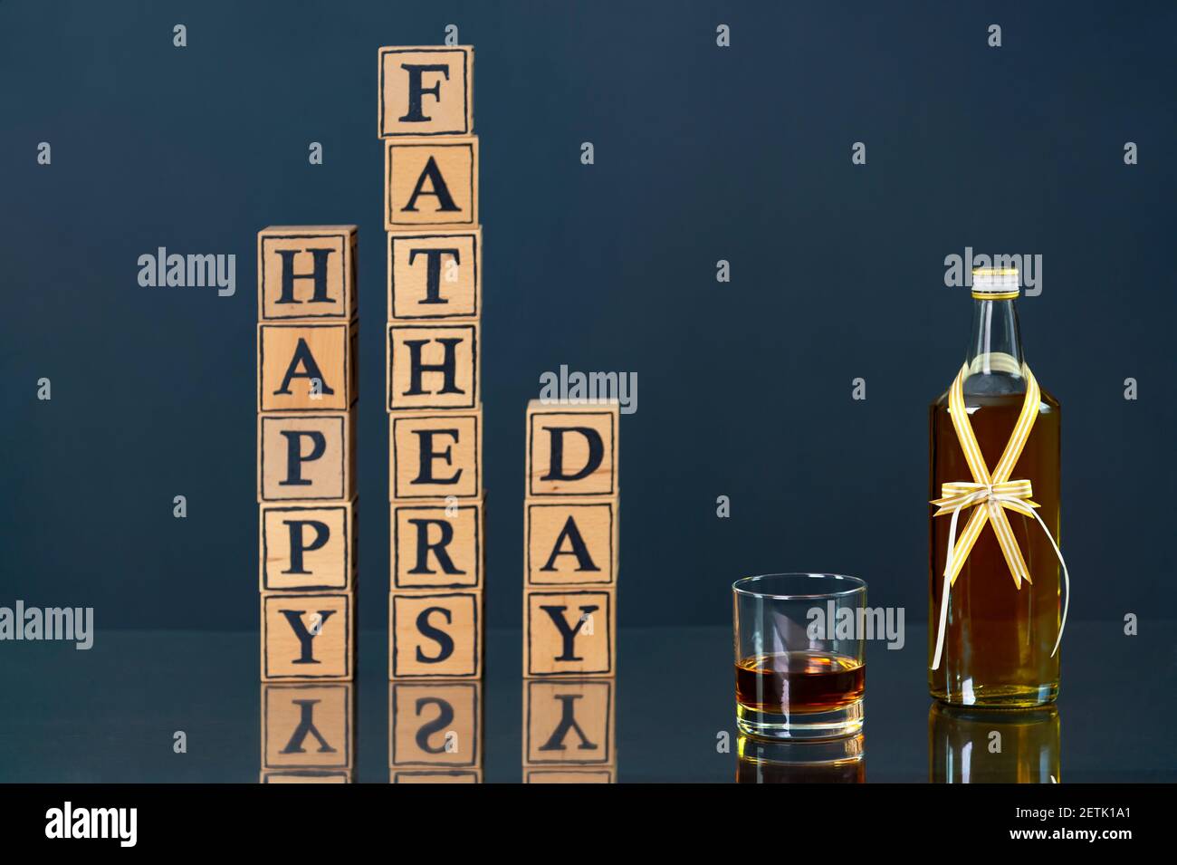 Wooden letters form English text: happy father's day. Next to it is a bottle of whiskey. Father's day gift idea. Stock Photo