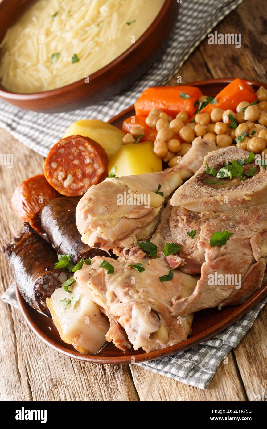 Cocido or cozido is a traditional stew eaten as a main dish in Spain, Portugal, Brazil close-up on a plate on the table. Vertical Stock Photo