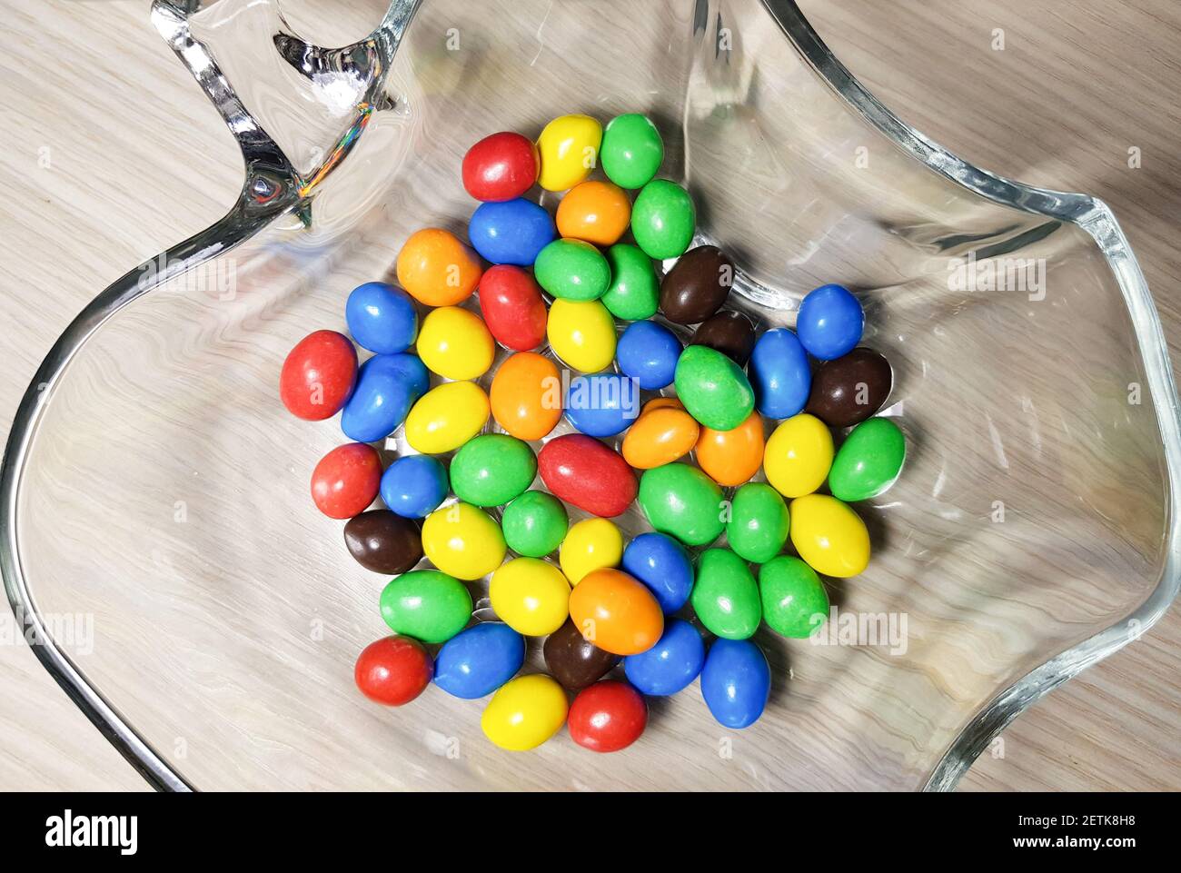 Multicolored chocolate-covered nuts in a transparent plate Stock Photo