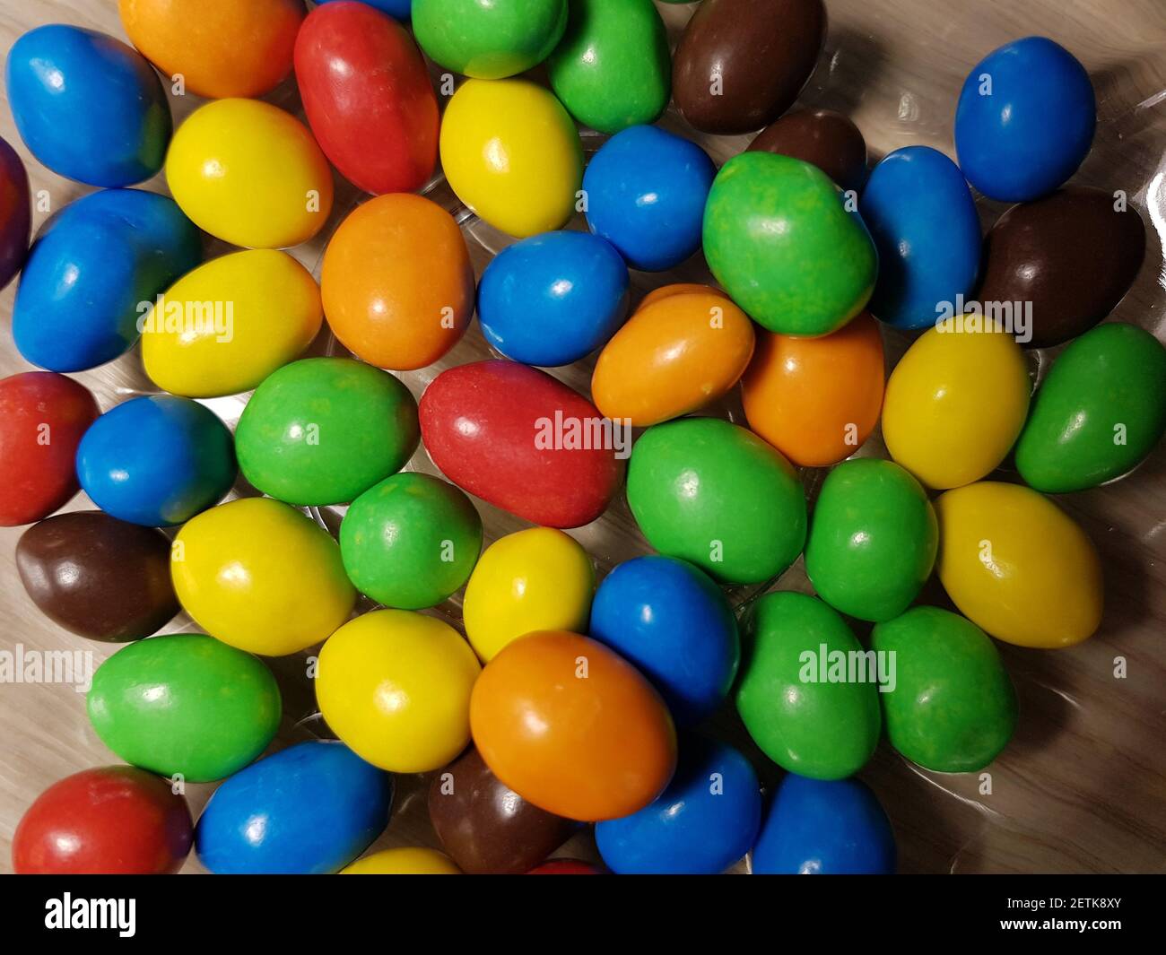 Multicolored chocolate-covered nuts in a transparent plate Stock Photo