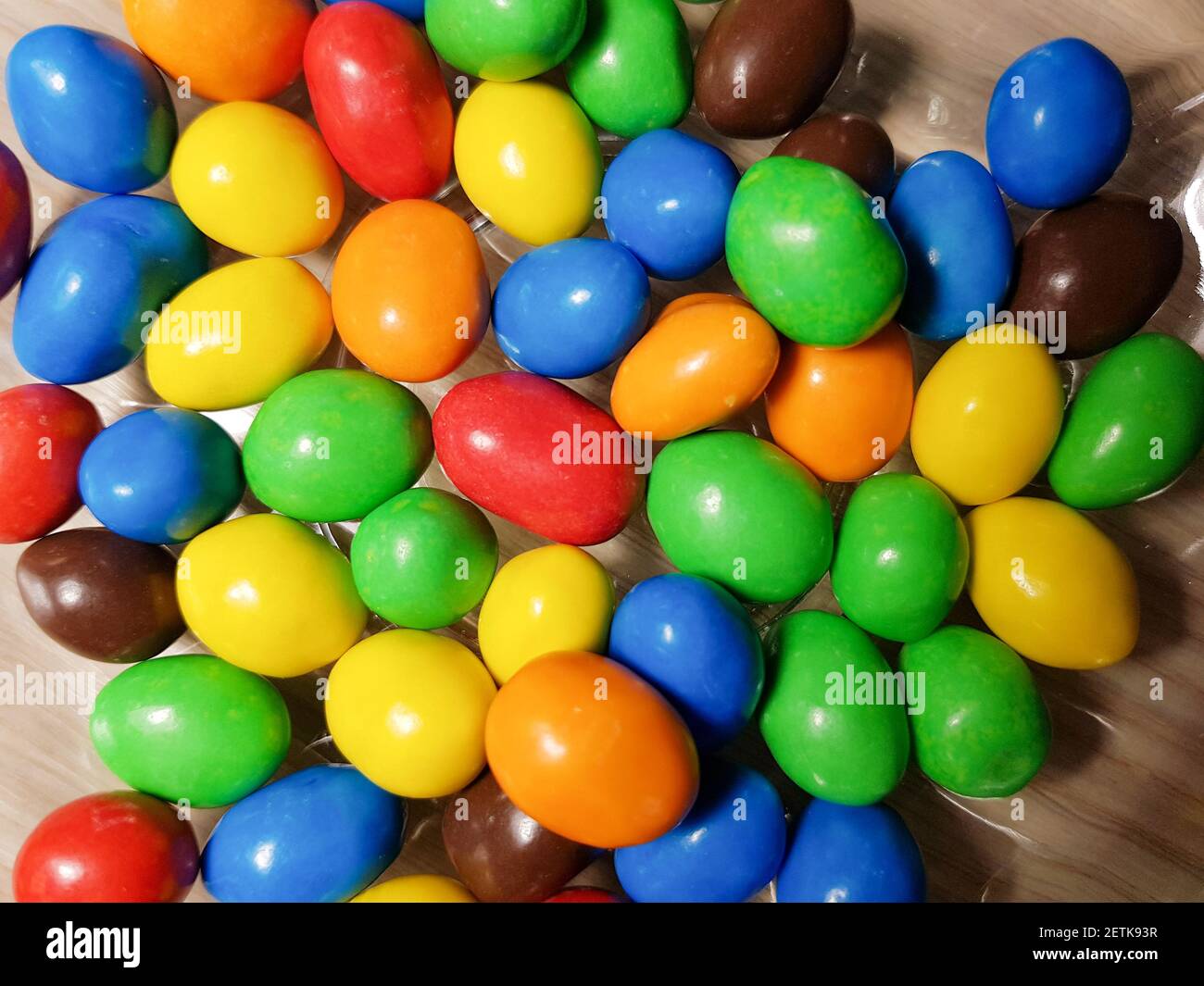Multicolored chocolate-covered nuts in a transparent plate Stock Photo