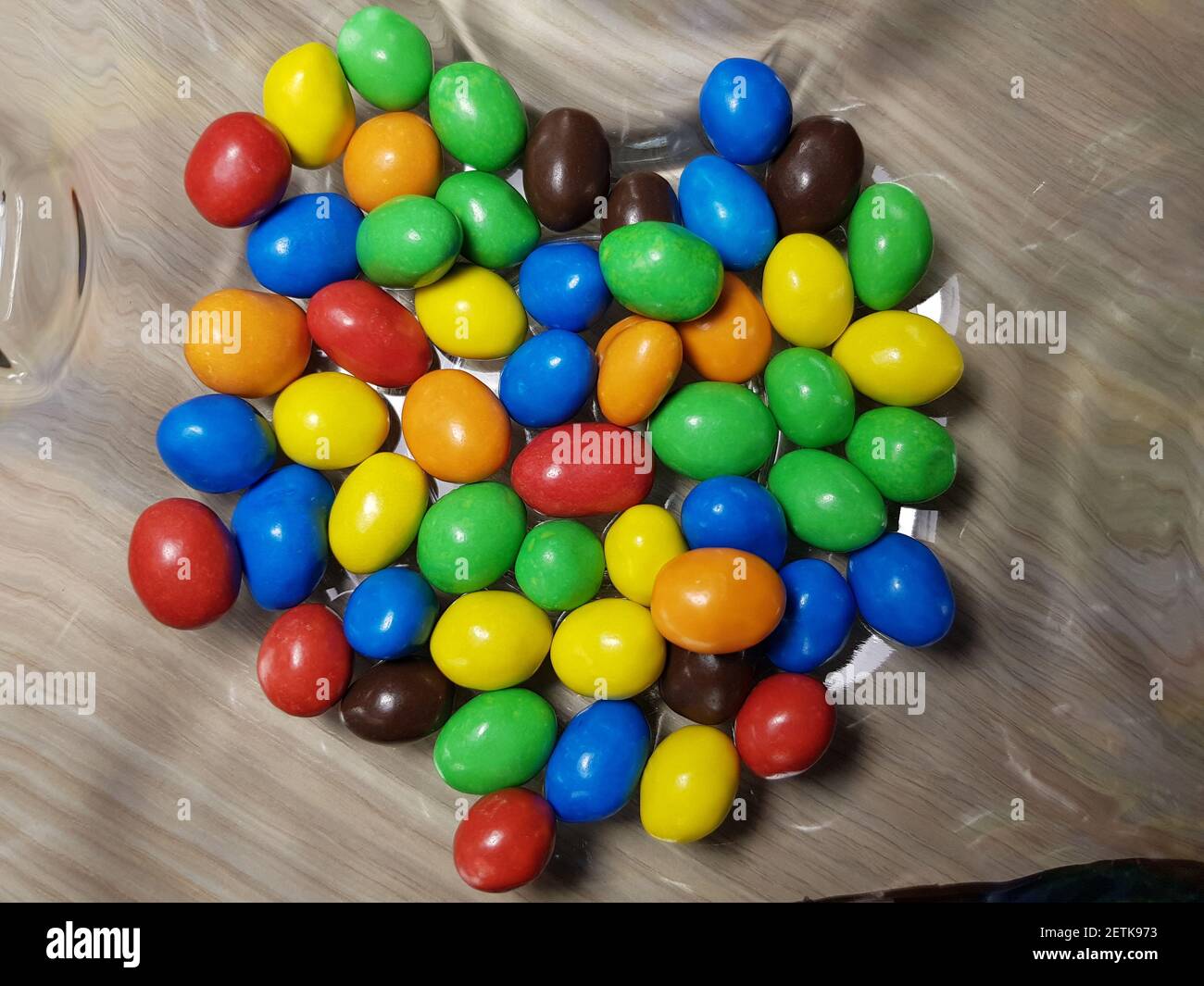 Multicolored chocolate-covered nuts in a transparent plate Stock Photo