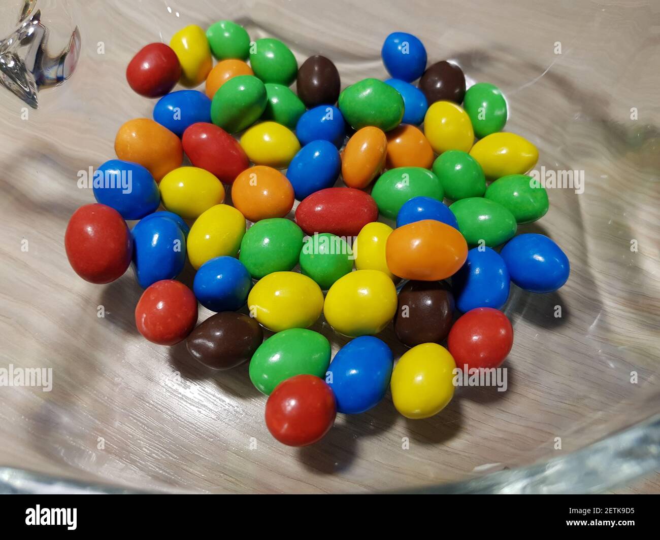 Multicolored chocolate-covered nuts in a transparent plate Stock Photo