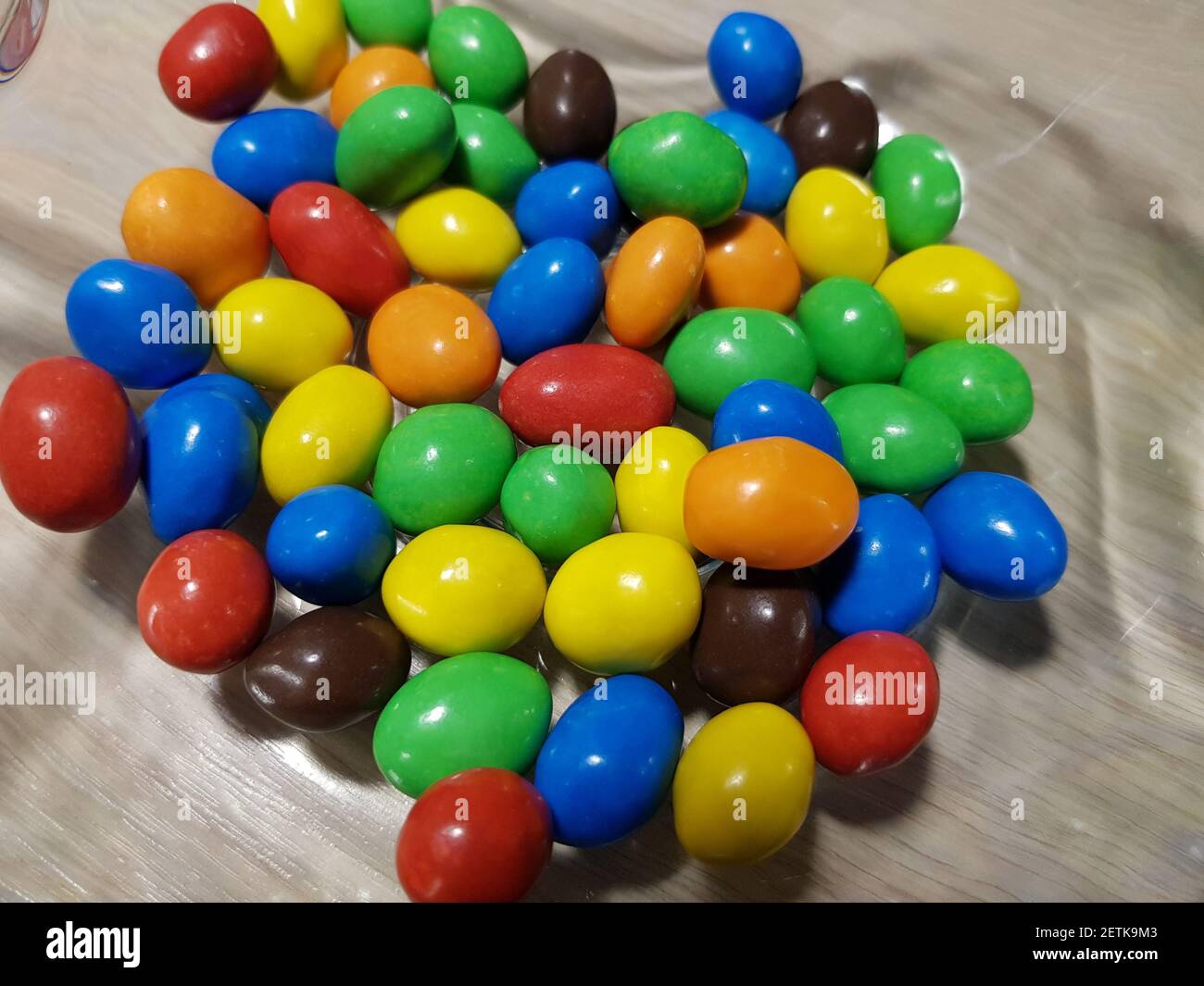 Multicolored chocolate-covered nuts in a transparent plate Stock Photo