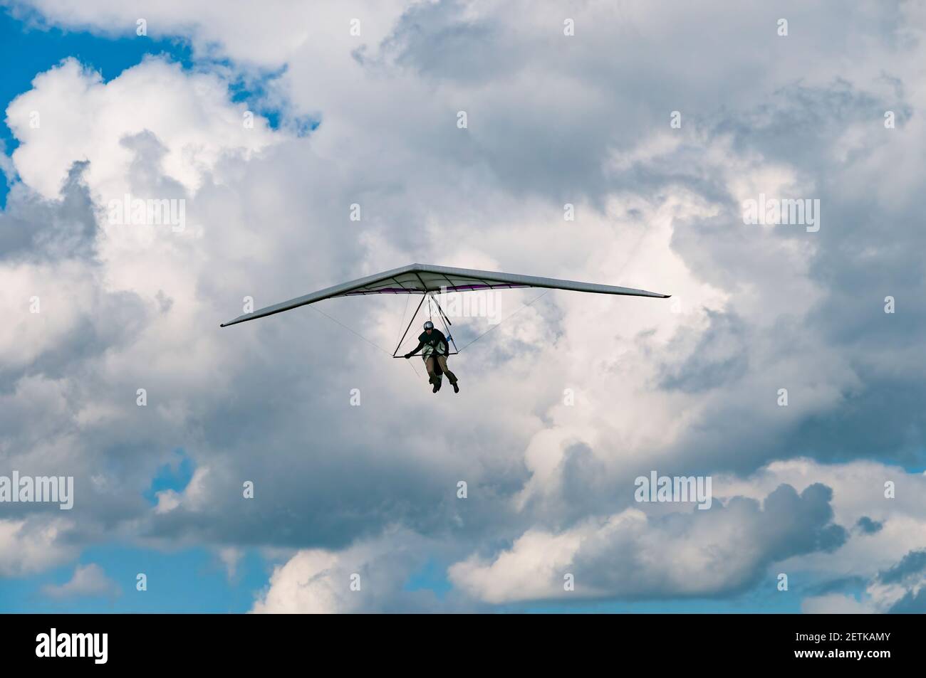 Hang glider pilot prepares to land with cloudy sky on the background. Extreme sports. Insurance for extreme sports Stock Photo