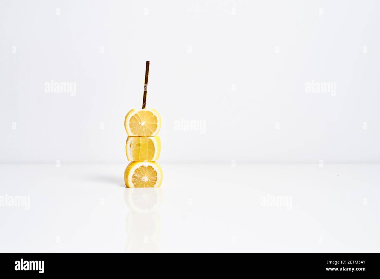 Lemonade concept. Yellow lemons and golden paper straw on white background Stock Photo