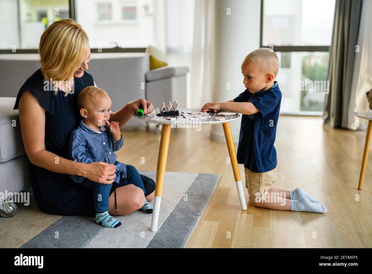 Mother or nursery teacher teaches her children to work with colorful play clay toys Stock Photo