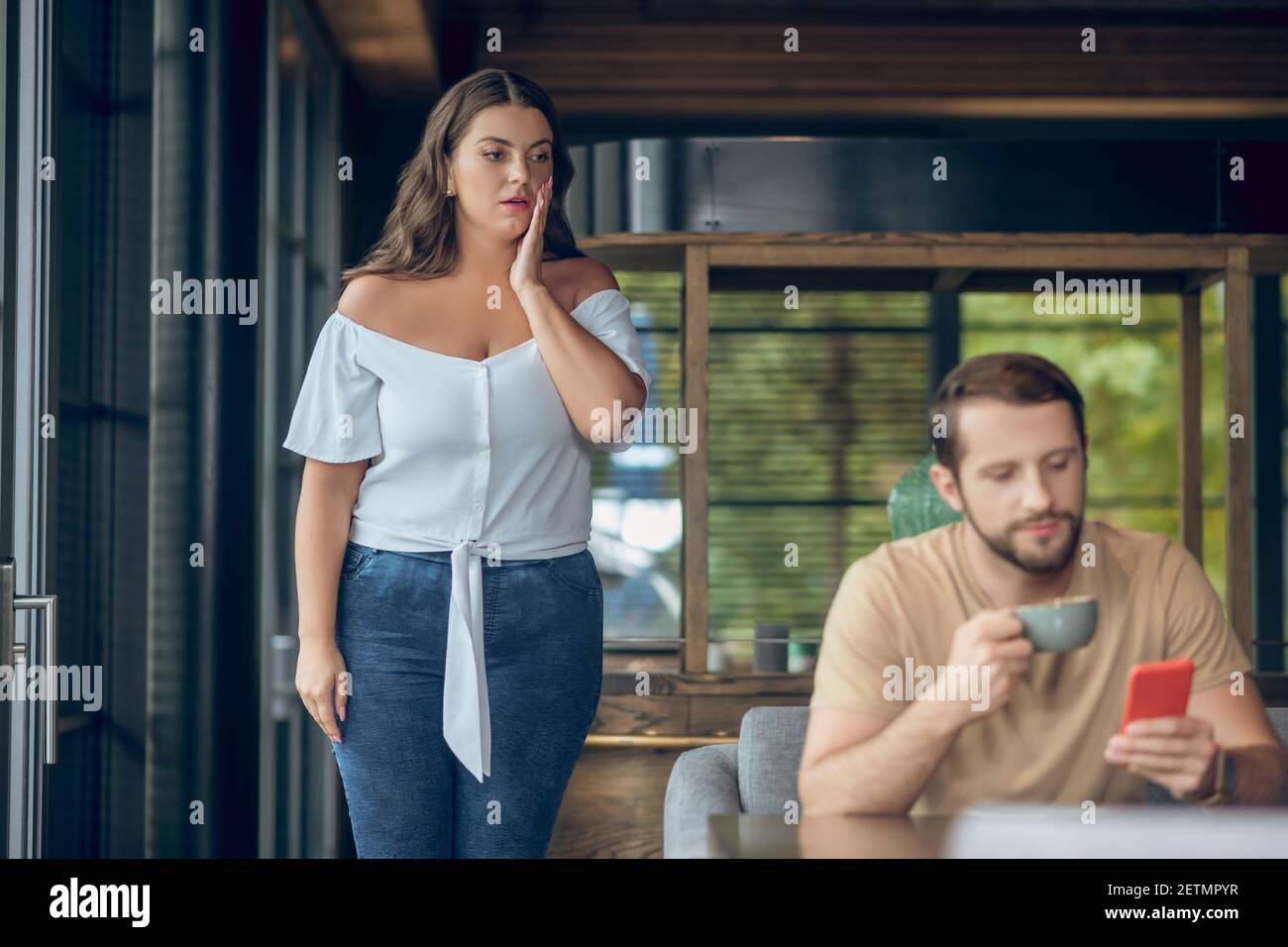 Surprised woman near table and man with smartphone Stock Photo