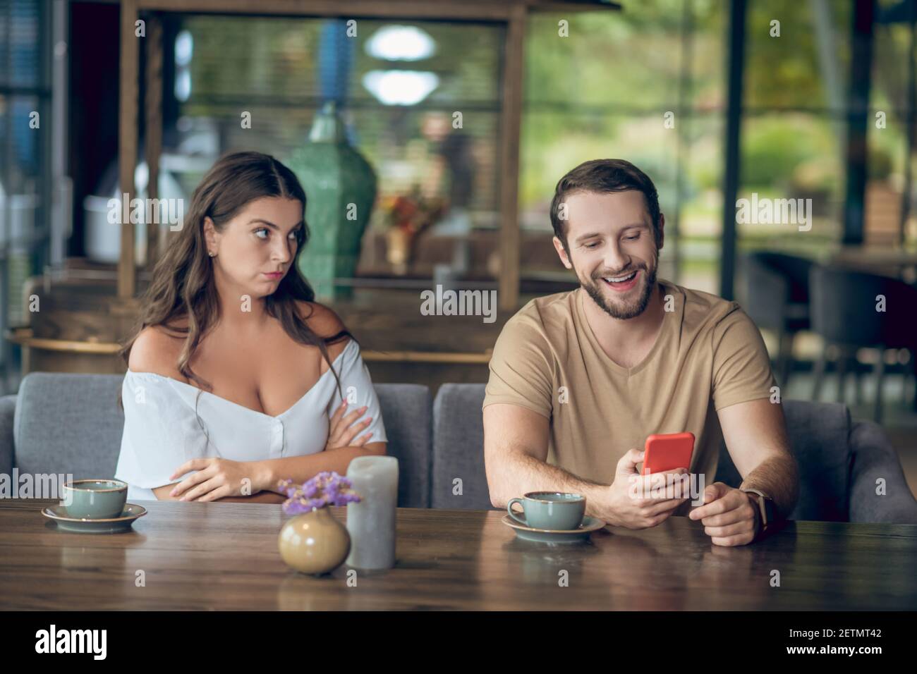 Laughing man with smartphone and sad woman Stock Photo