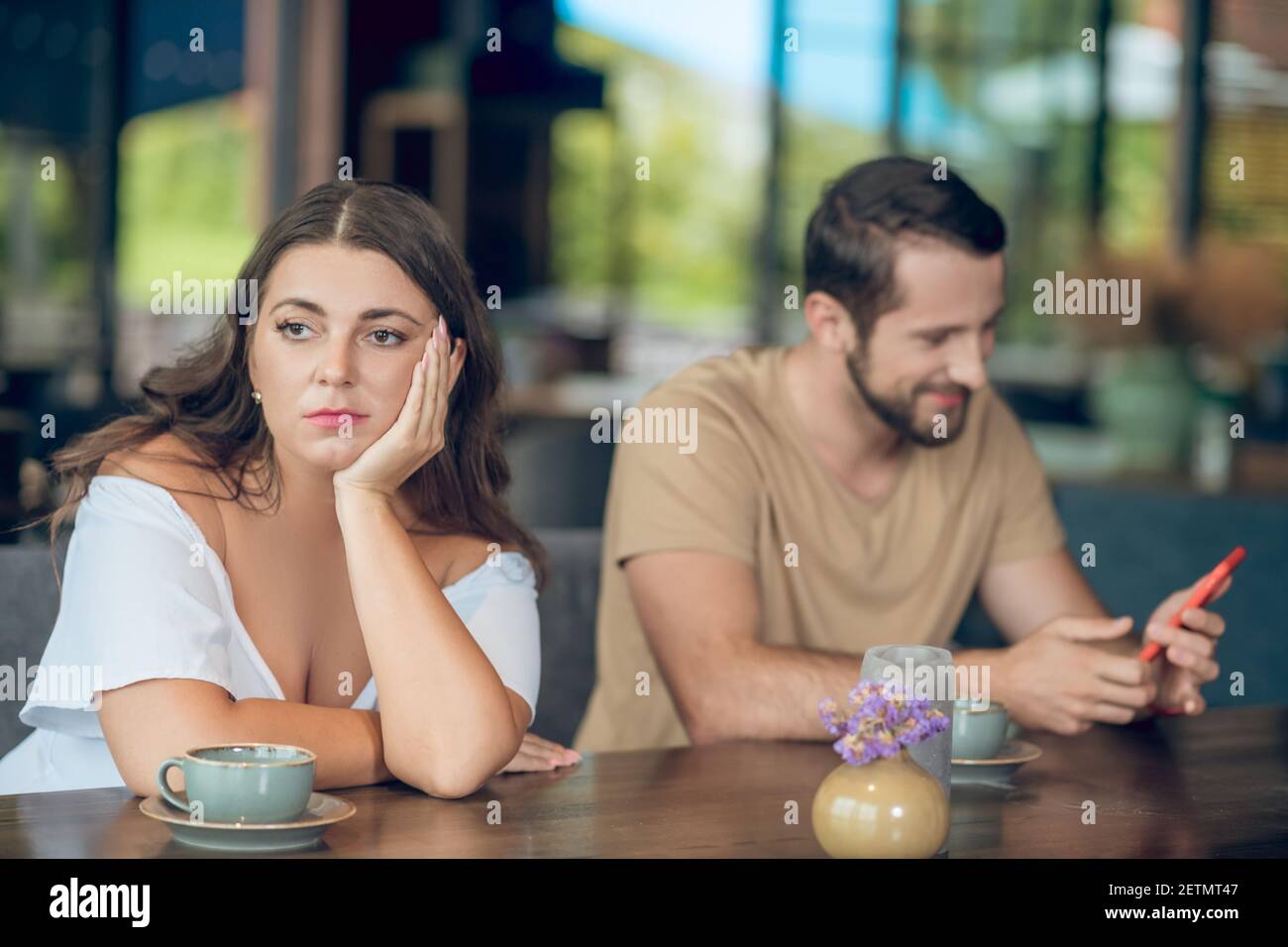 Sad turning away woman and cheerful man with smartphone Stock Photo