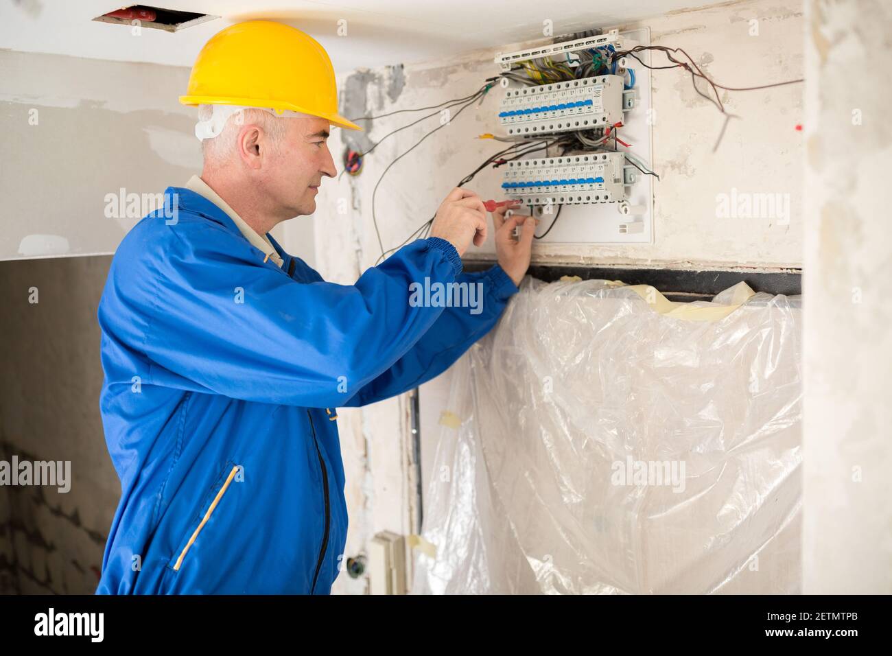 Senior electrotechnician connecting wiring system and completing the preparation of the electrical circuit home network Stock Photo