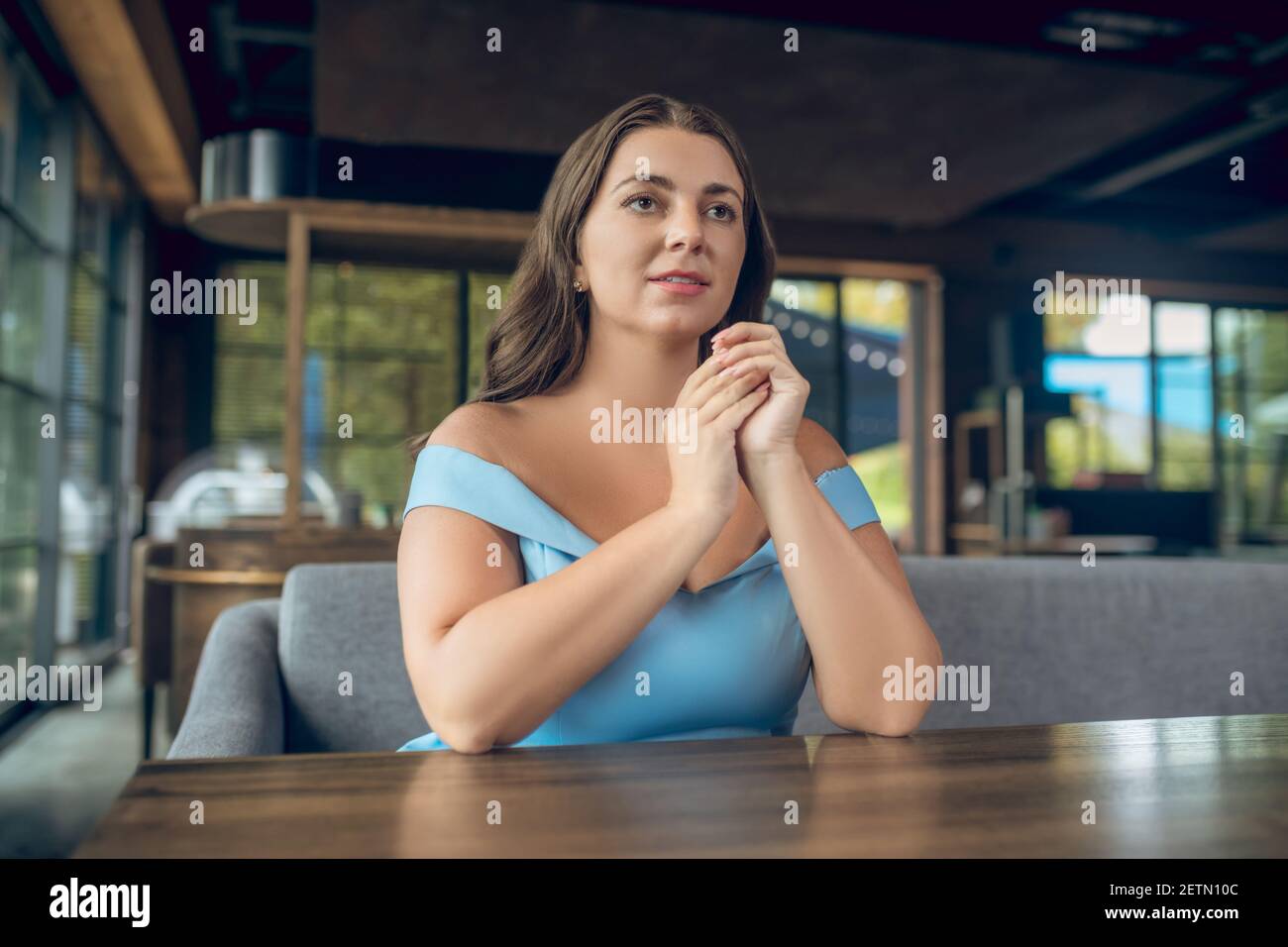 Beautiful serious woman sitting in summer cafe Stock Photo