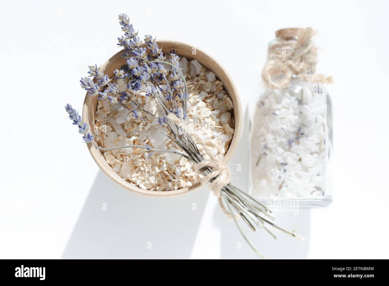 Cardboard jar with oatmeal and sea salt and a small bouquet of lavender. Sea salt in glass jar with cork stopper. Spa products for skin cleansing Stock Photo