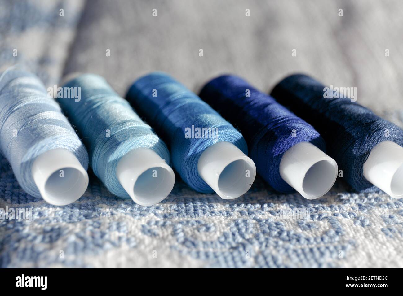 Blue thread. Set of sewing thread coils on white natural fabric with  embroidery. Several reels of thread in different shades of blue. Selective  focus Stock Photo - Alamy